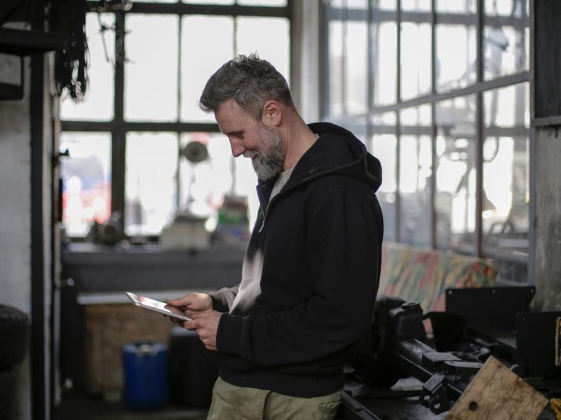 Techniker in einer Werkstatt erfasst einen Auftrag auf dem Tablet