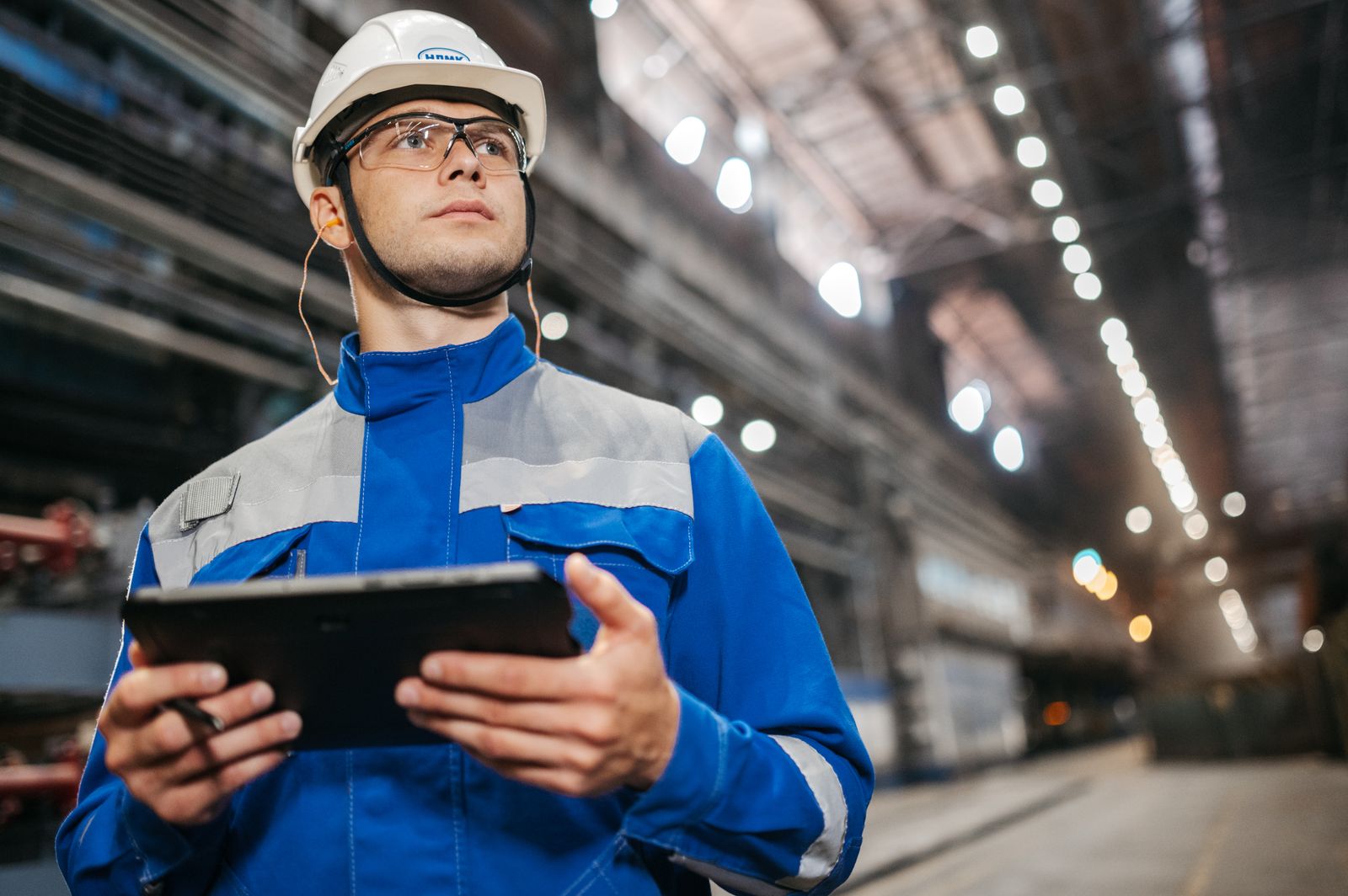 Mitarbeiter im Maschinen- und Gerätehandel arbeitet digital mit Tablet an technischen Anlagen